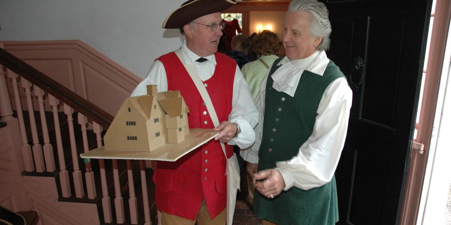 2 men in costume one holding house